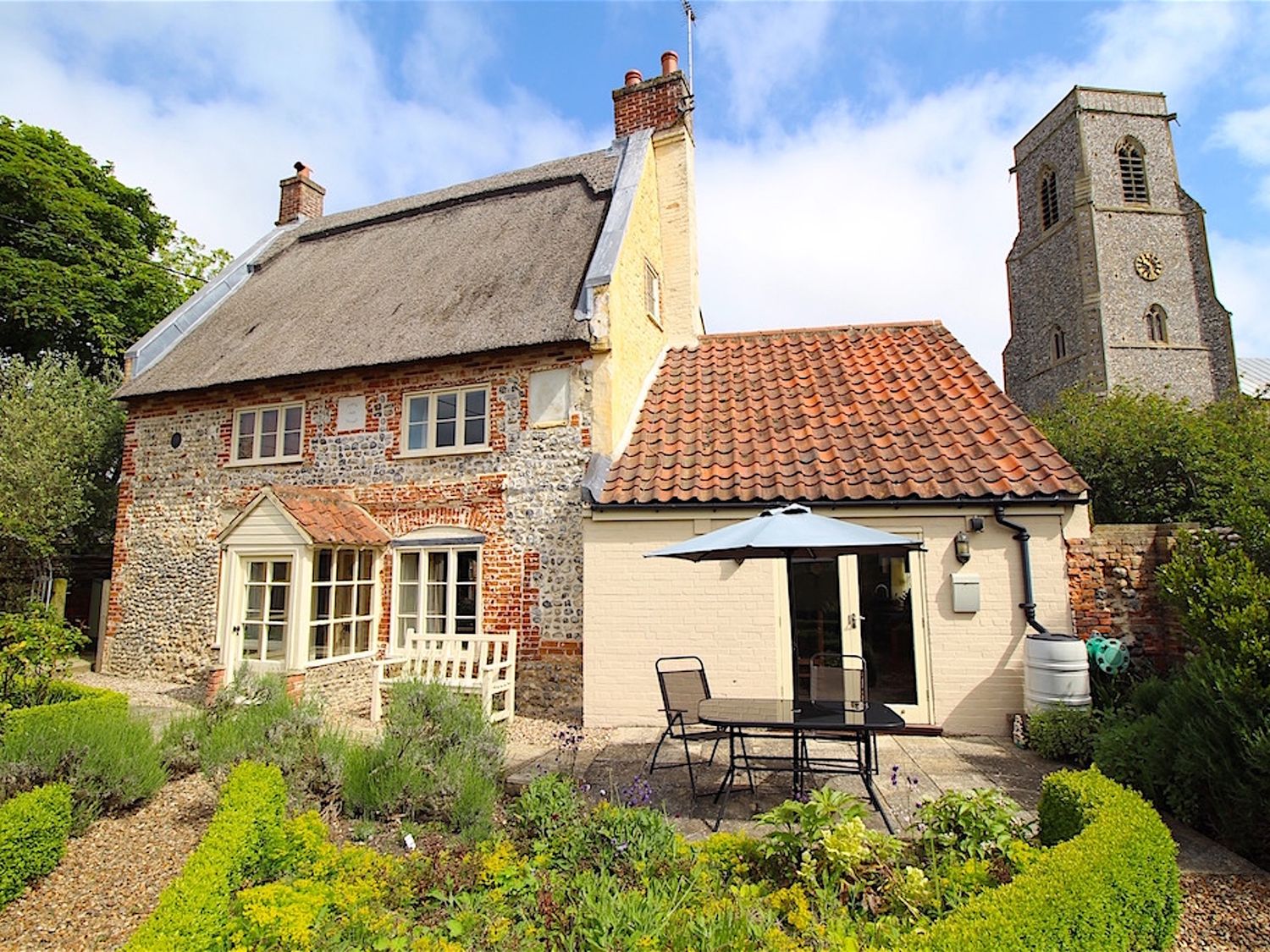 An outdoor area with a table and chairs at Thatch Cottage in Trunch