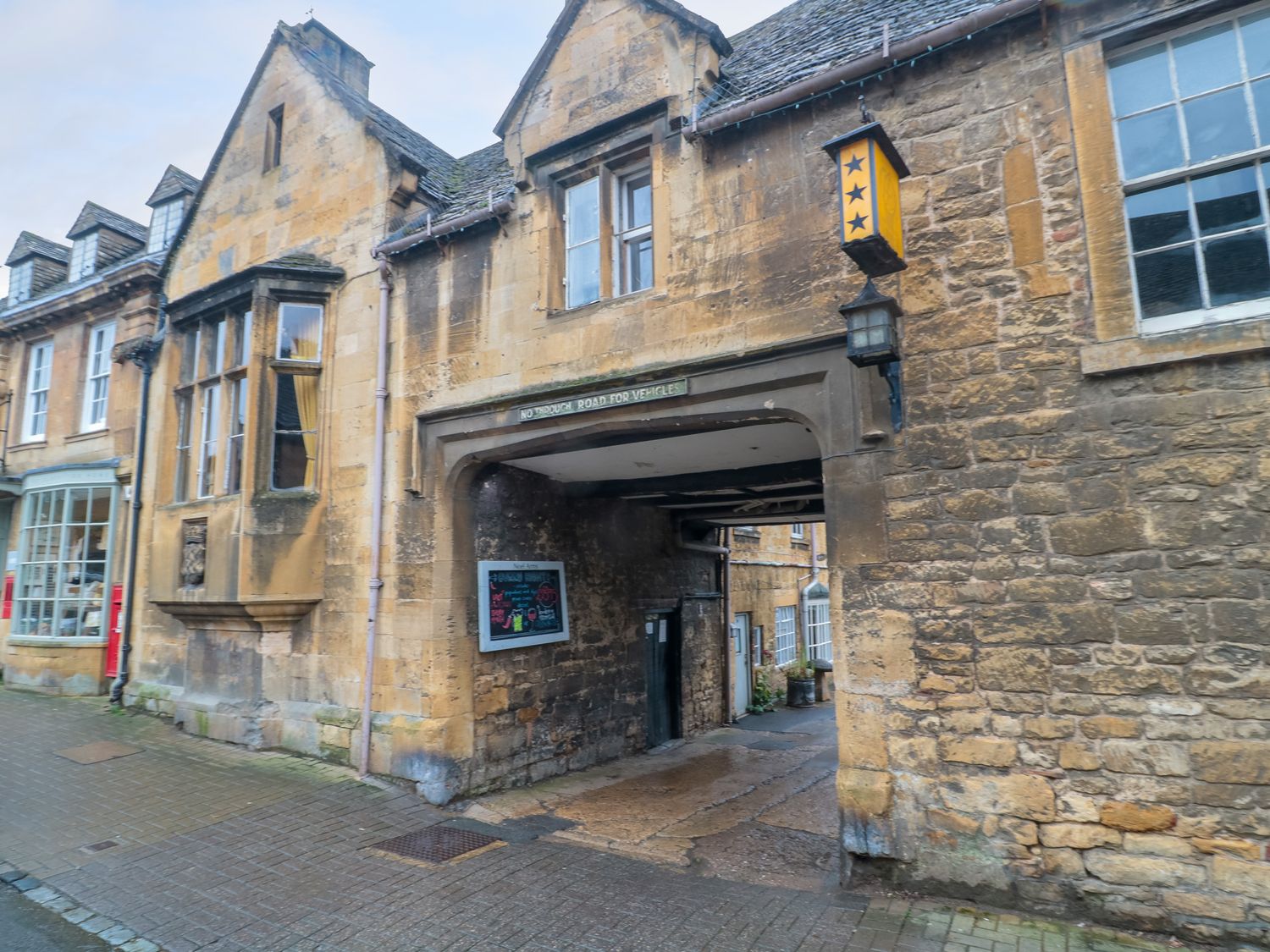 Old stone building with an archway entrance and windows on a paved street at 4 Noel Court in Chipping Campden