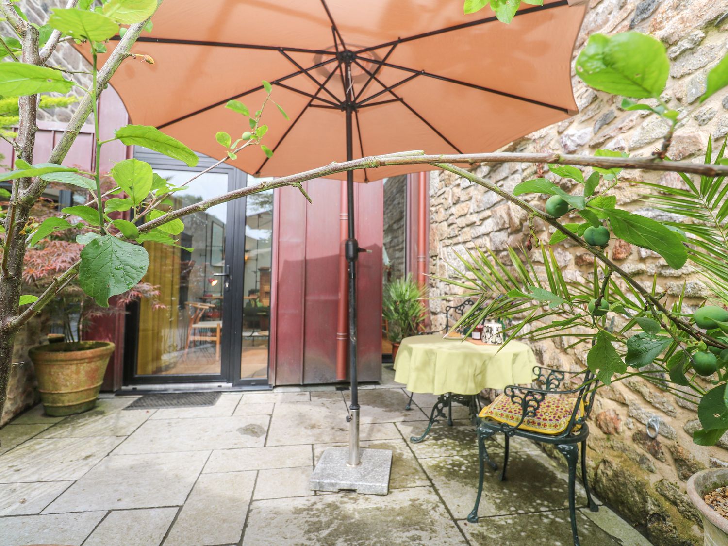 An outdoor area with a table and chair under an umbrella at The Stables in St Just