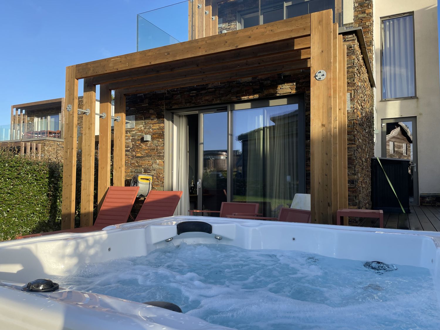 A hot tub with chairs and a wooden deck at Villa 80 in Carbis Bay