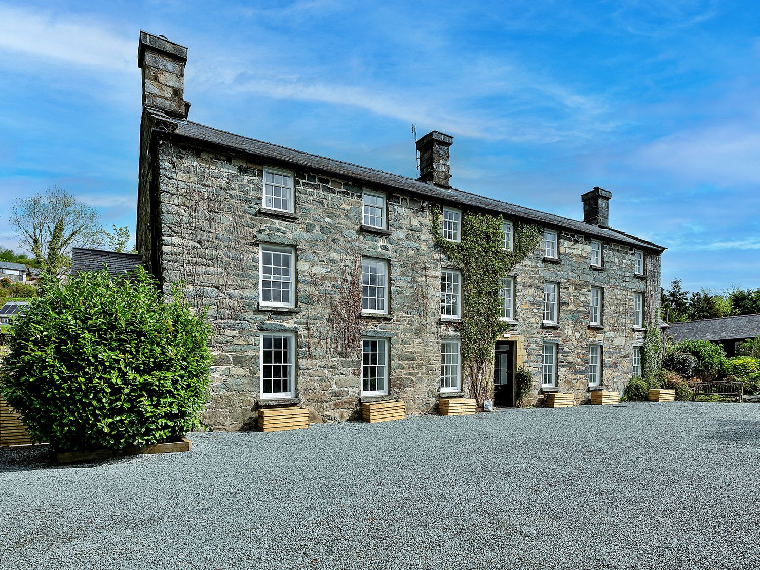 A stone house with windows and a gravel driveway at Snowdonia Manor in Dolgellau