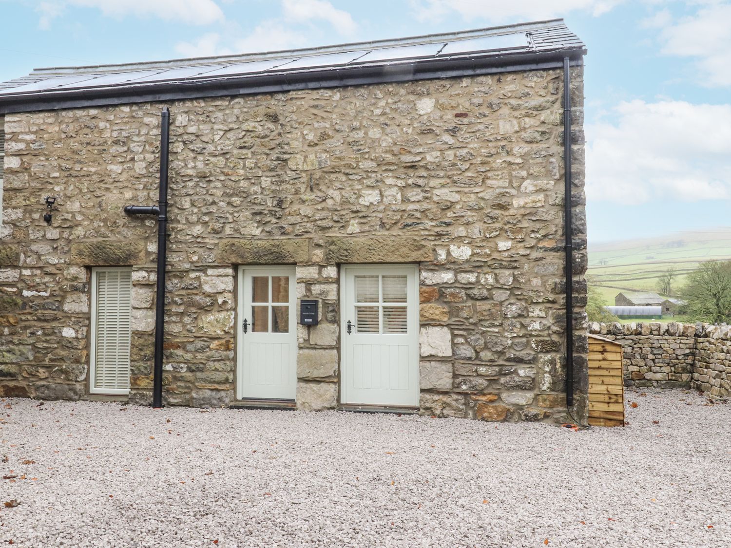 An outdoor area with stone walls and two doors at Henside Cottage in Settle