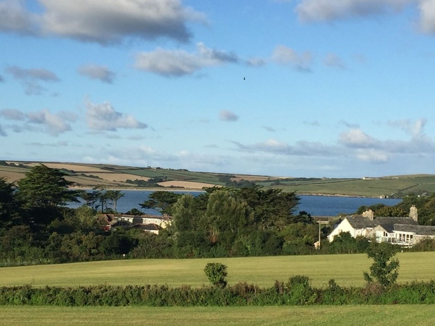 A countryside landscape with trees houses and a body of water under a partly cloudy sky at Seaworthy in Daymer Bay