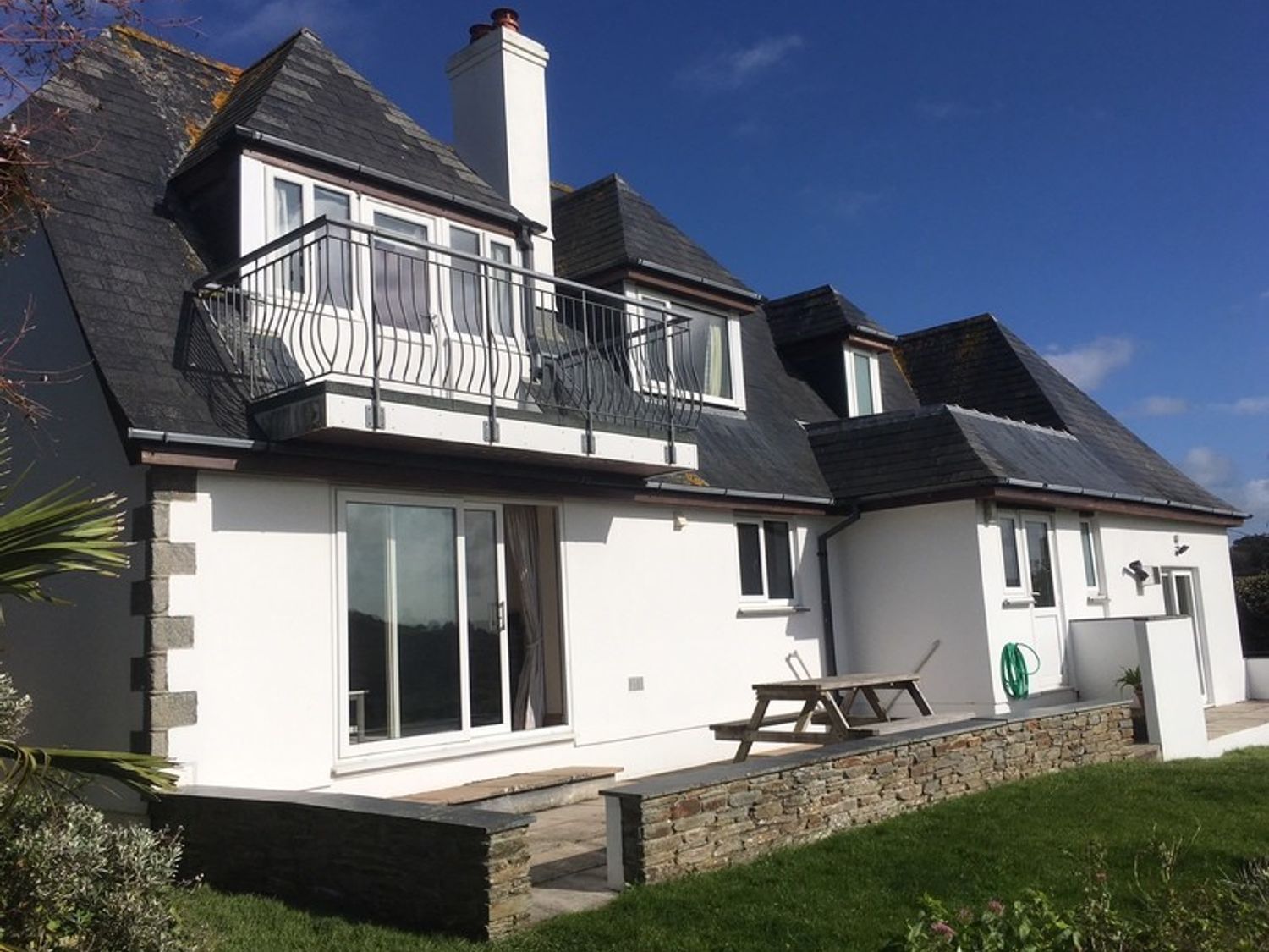An exterior view of a house with a balcony patio area and garden at Seaworthy in Daymer Bay