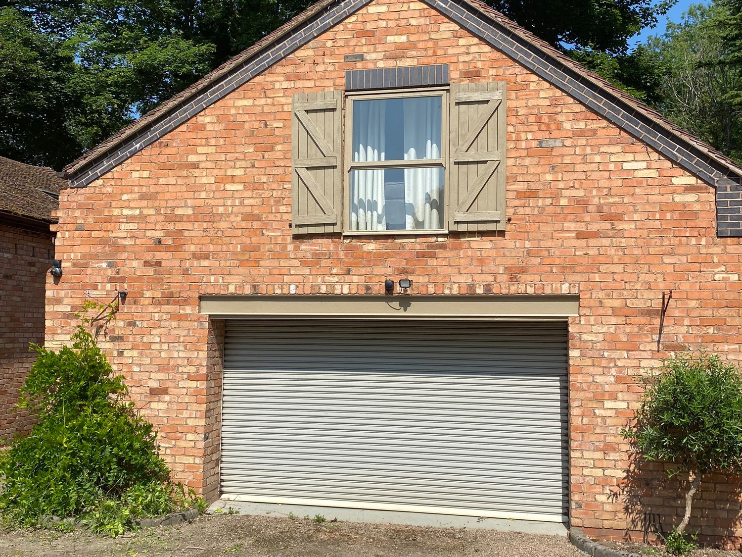 A garage with a window and bushes at Old Forge Apartment Cookley