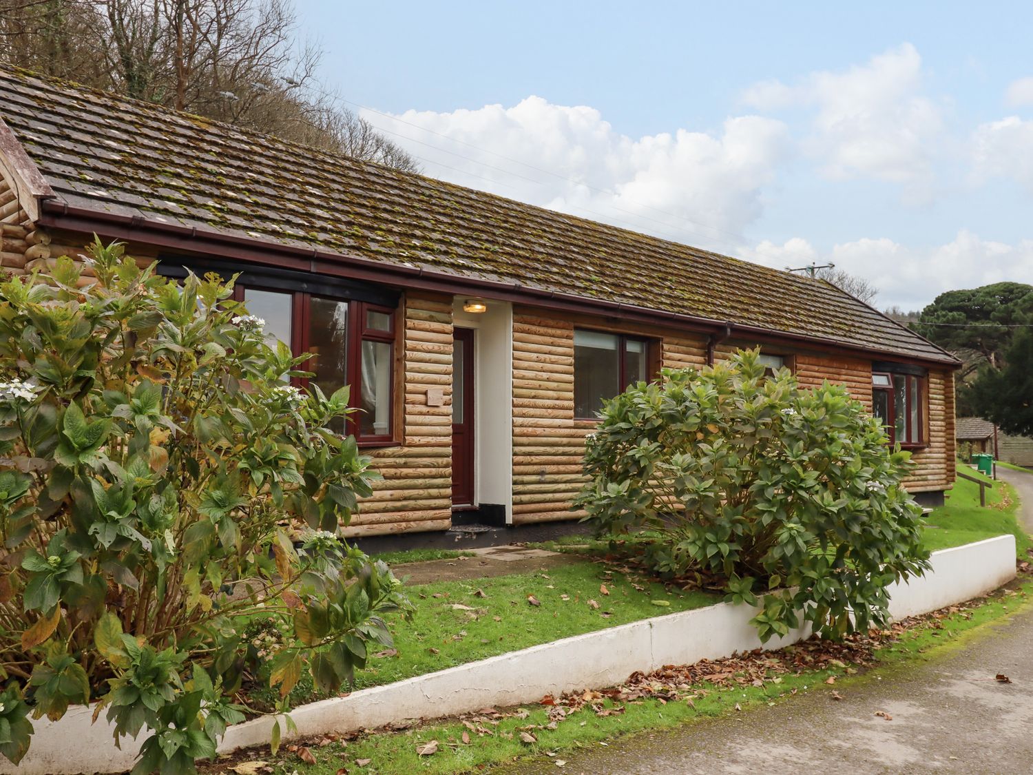 A single story wooden house with bushes in front at Castle View Lodge in Ilfracombe
