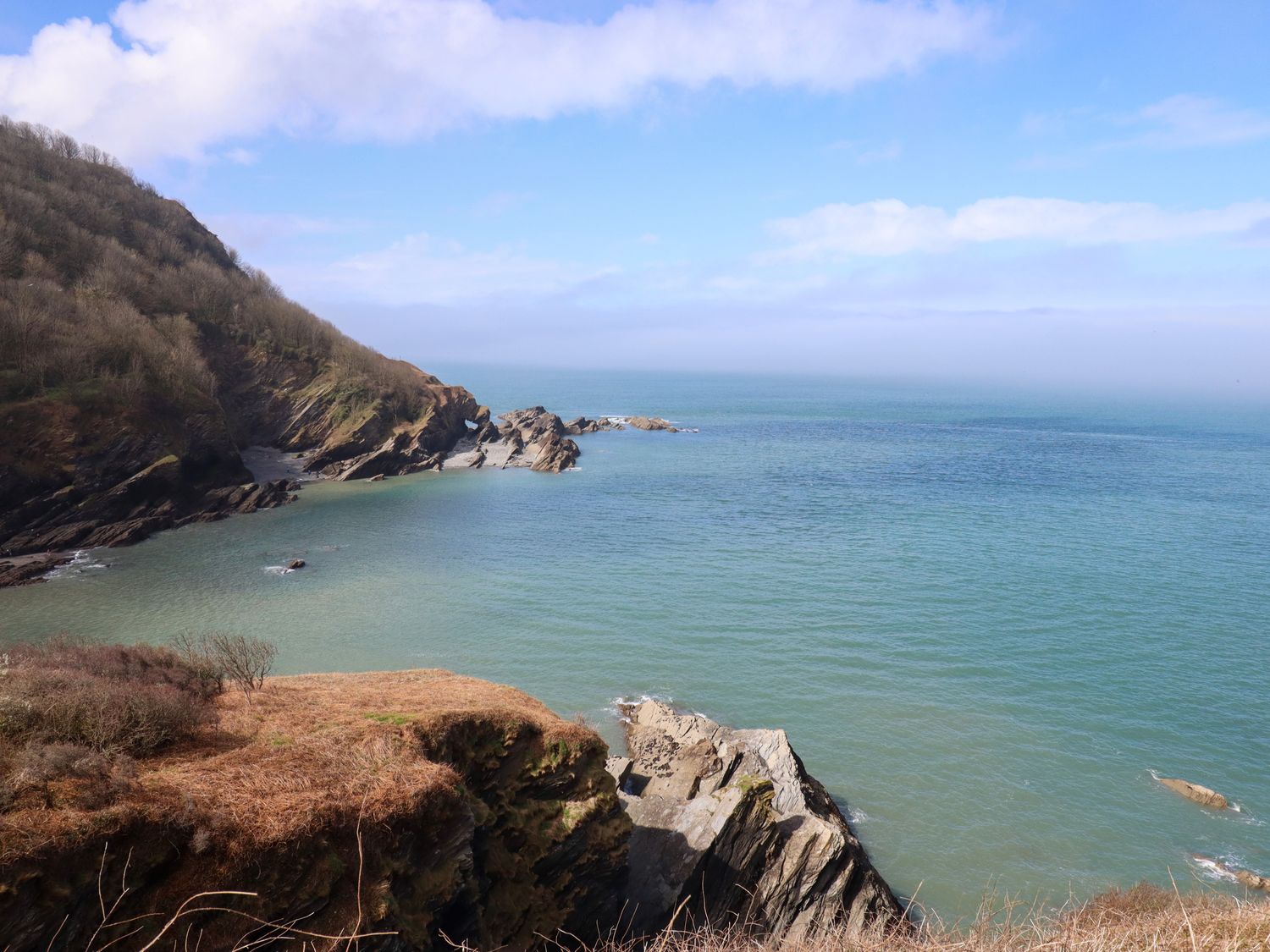 A coastal landscape with rocky cliffs and calm sea at Castle View Lodge in Ilfracombe