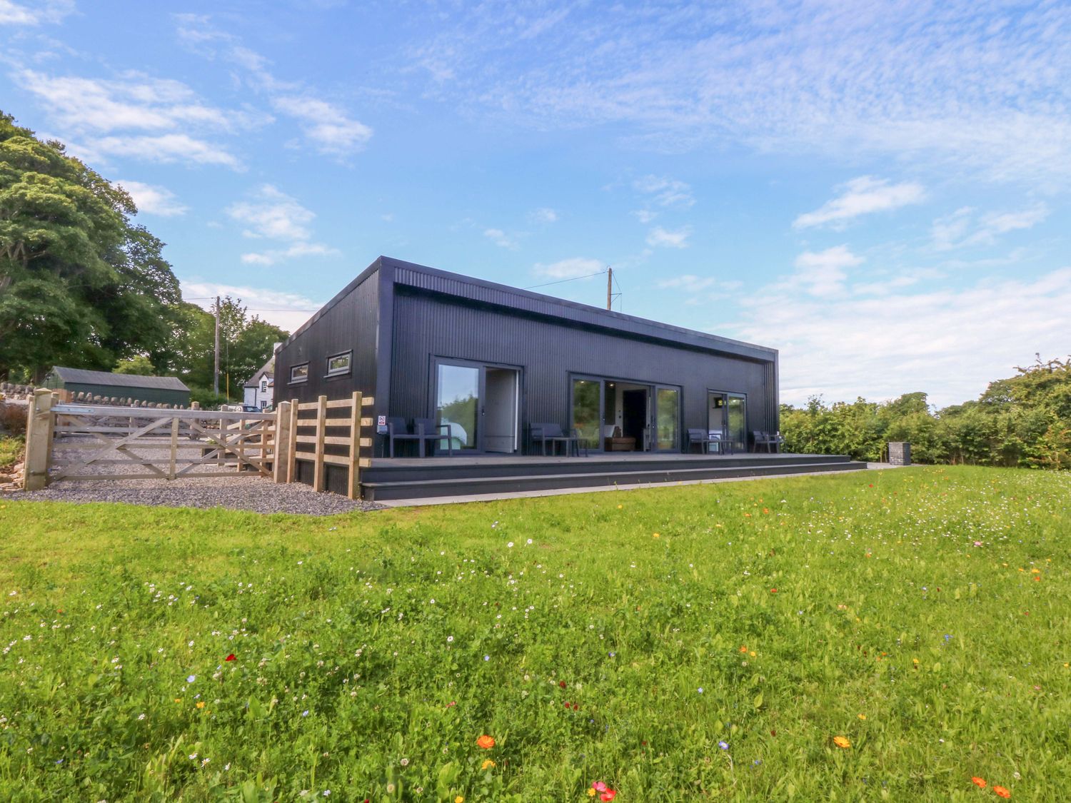 An outdoor view of a house with patio and fence at Y Cwt Moelfre