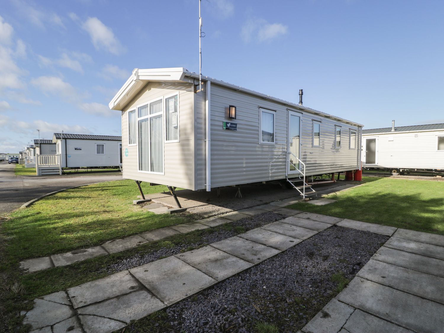 A mobile home with steps and a lawn at Lido Gold 205 Prestatyn