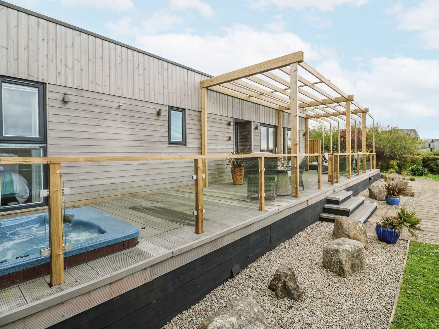 An outdoor area with a hot tub and wooden deck at Petroc in Portreath