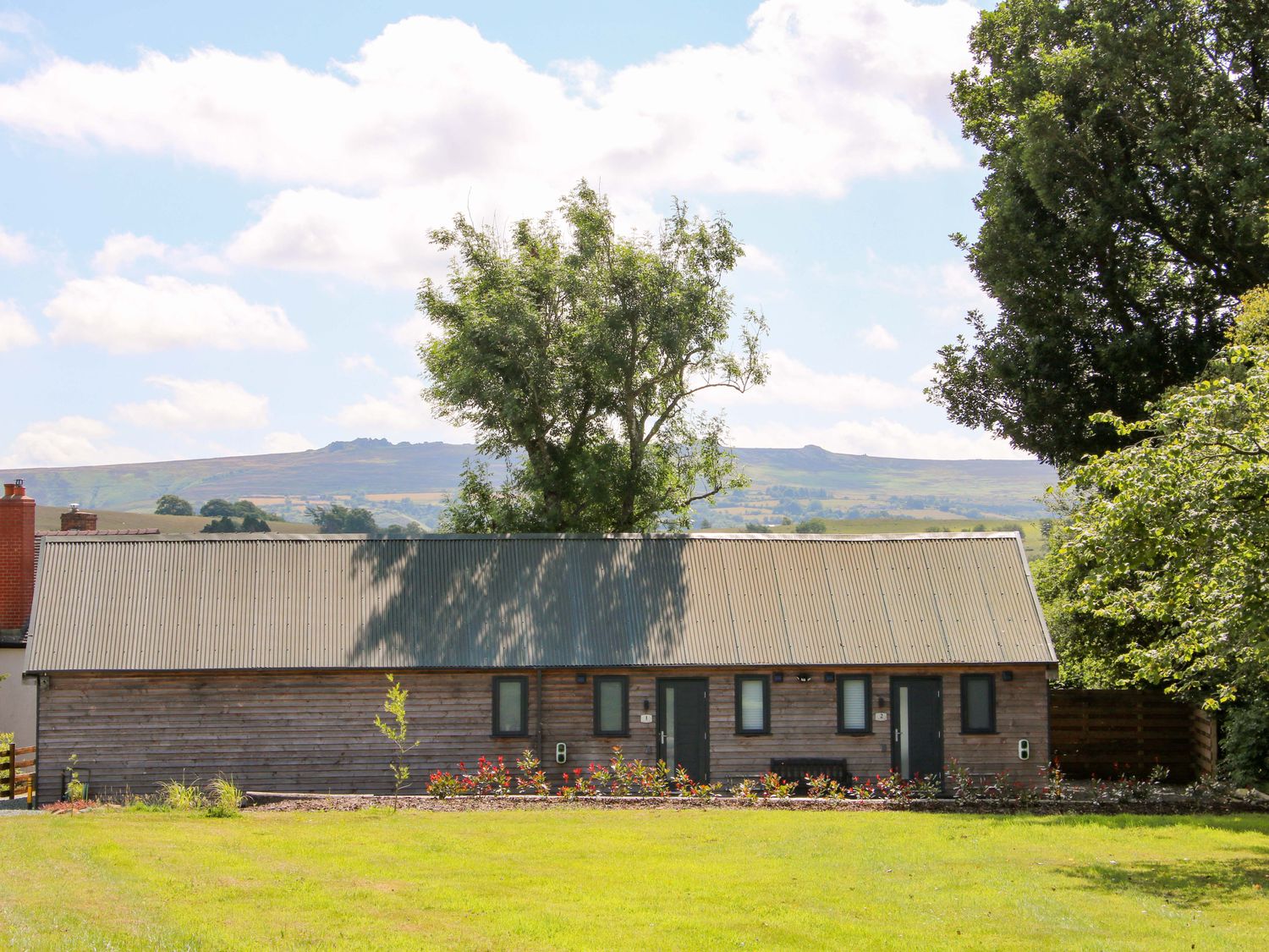 A building with a metal roof and trees at Stiper View Barn 1 Gravels Bank