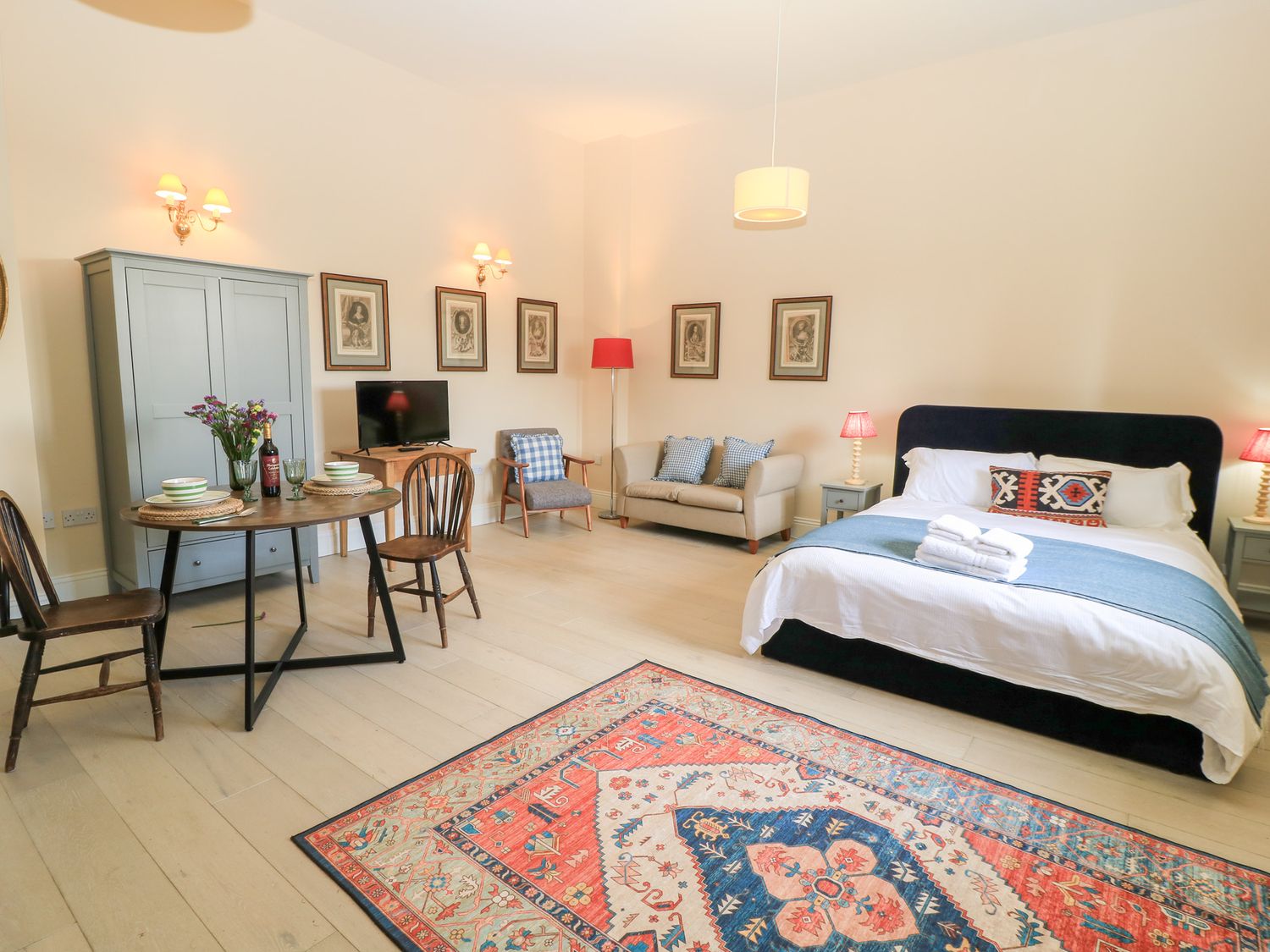 A bedroom with a bed sofa dining table chairs wardrobe and television at Woodcock Studio in Andoversford near Cheltenham