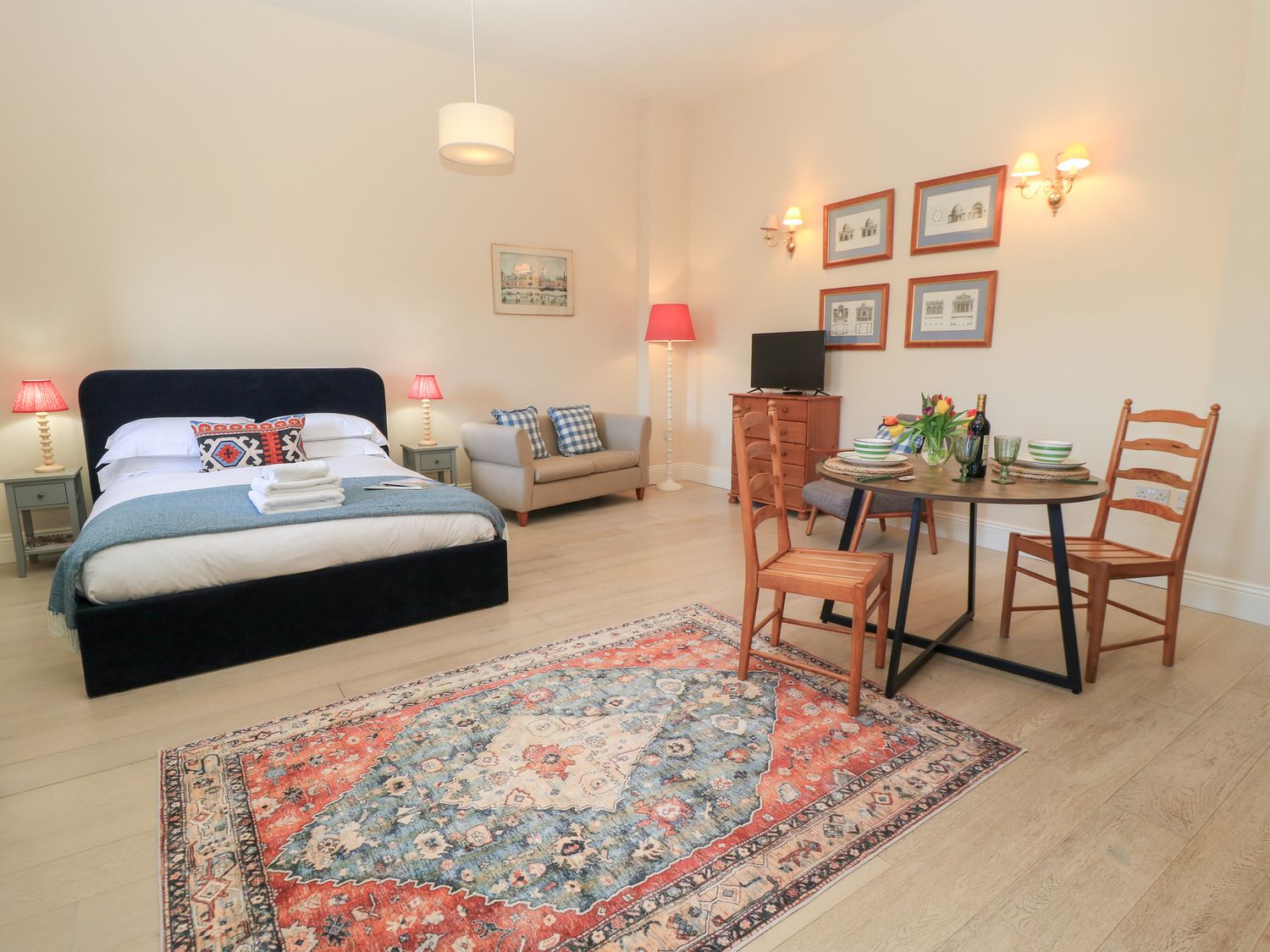 A bedroom with bed sofa dining table and chairs with a rug on the floor at Swallow Studio in Andoversford near Cheltenham