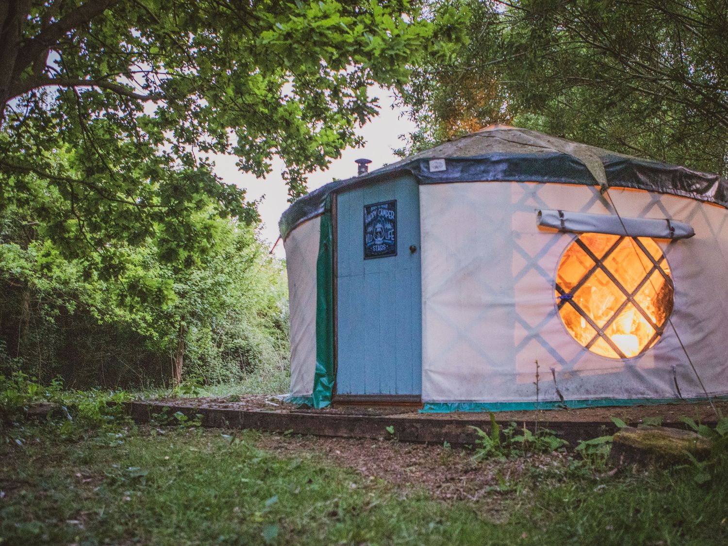 A yurt with a lit interior in a wooded area at Brandon House Farm Yurt Brandon Parva near Mattishall