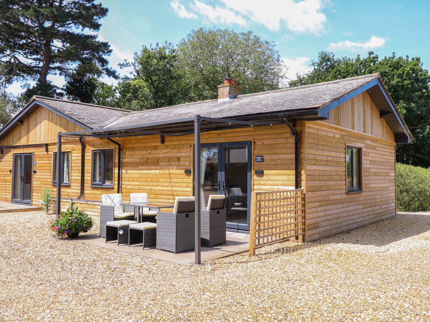A cabin with patio furniture outside at Rabbit Warren Lodge in Snettisham