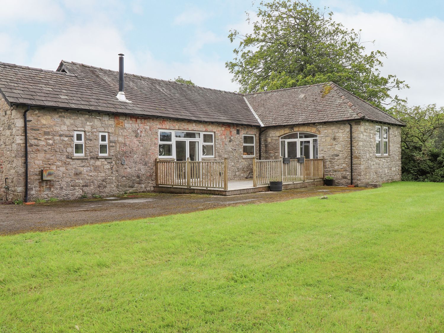 A house with a wooden deck and surrounding grass at The Gatehouse in 
