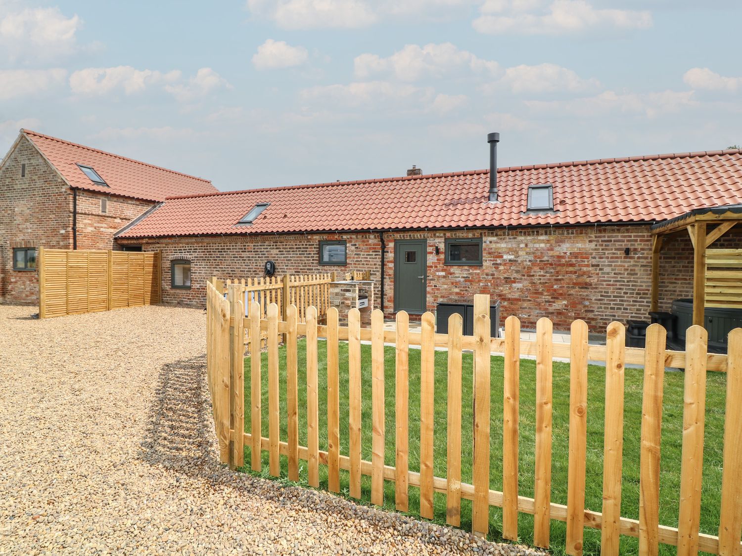 An outdoor view of a barn with a fence and grass at Buzzard Barn in Woodhall Spa