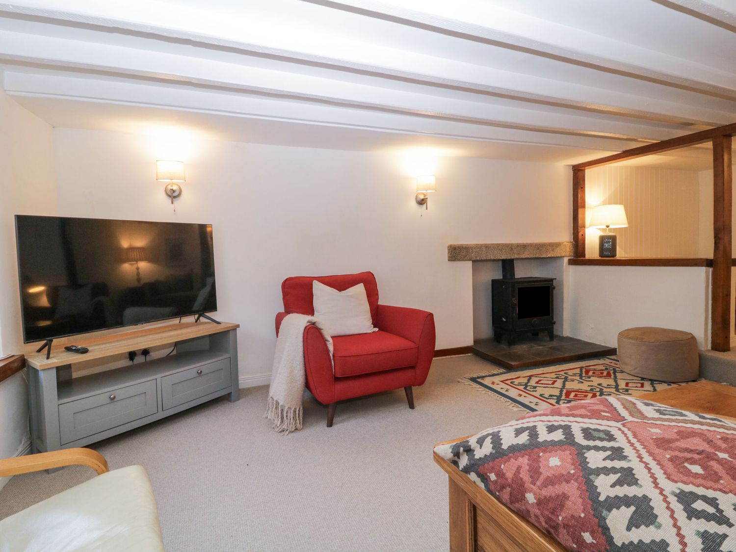 A living room with a red armchair a television on a stand and a wood stove at Springfield in Kingsand