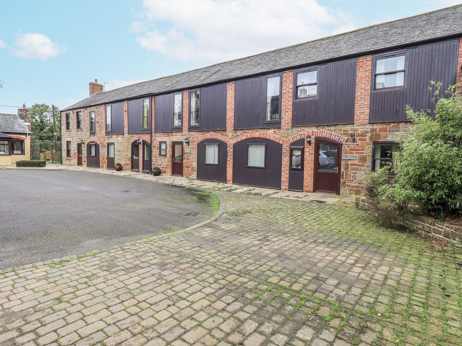 A building with windows and doorways in a courtyard at Millers Cottage Seaville near Wigton