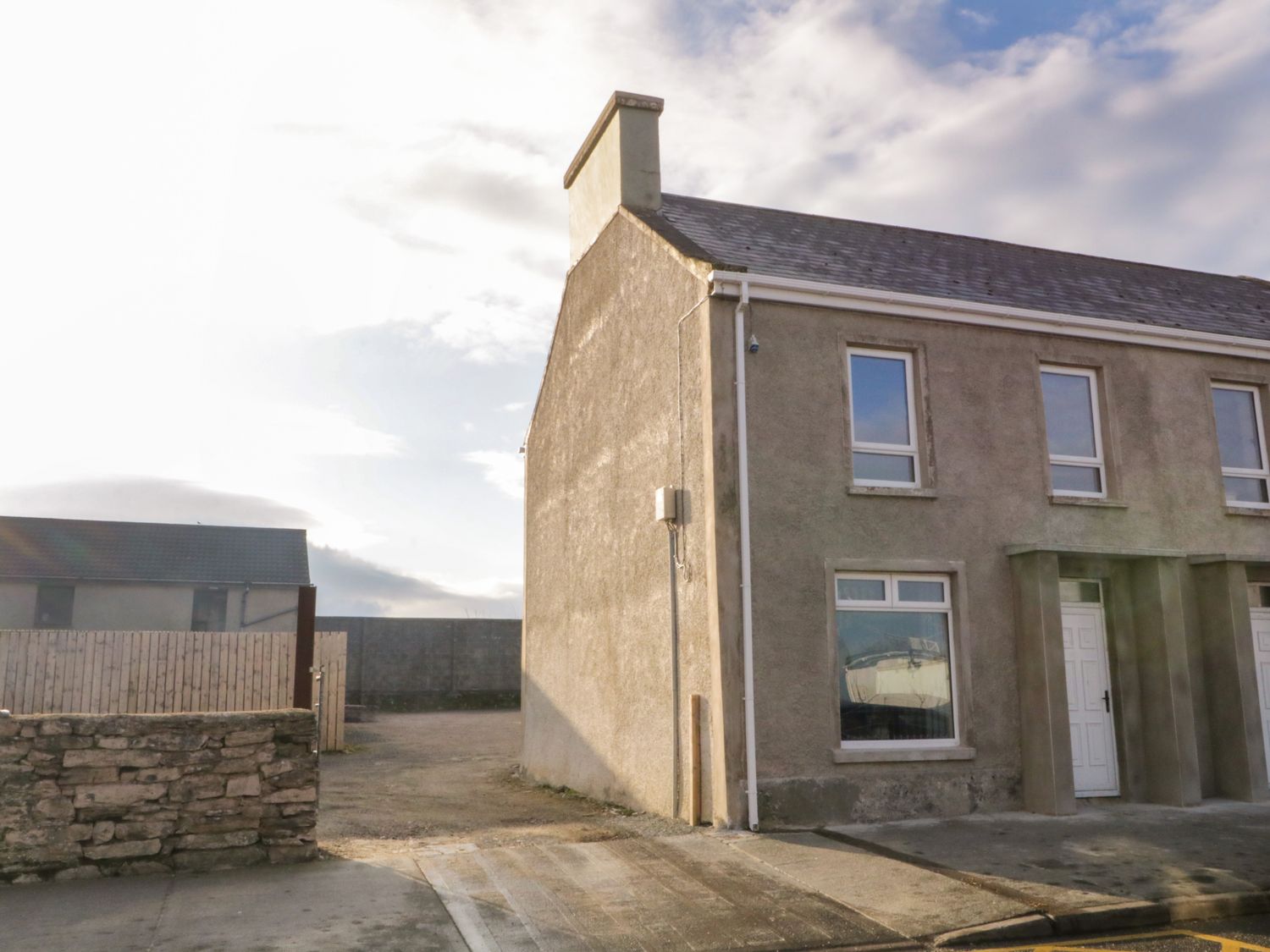 Exterior of a two-story semi-detached house with windows and doors on a paved street at Town House No 1 in Falcarragh County Donegal