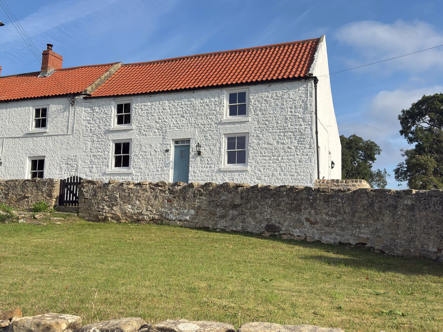 A white building with a blue door and windows at Peace Cottage in Langton near Gainford