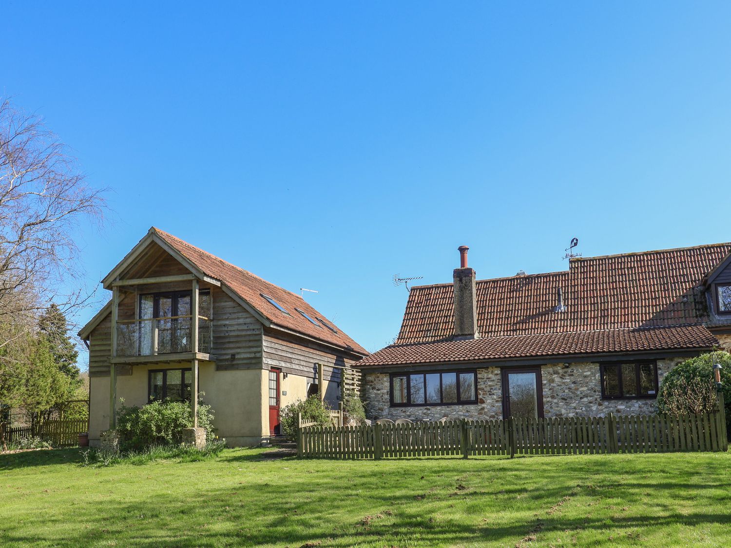 A view of a traditional stone and wood house with tiled roof and a small wooden fence at Apple Loft in Upottery