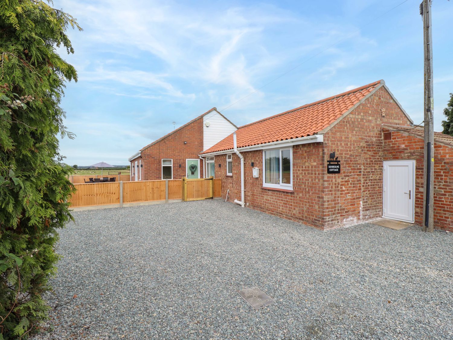 An outdoor area with a cottage and gravel driveway at Denholme in Hogsthorpe