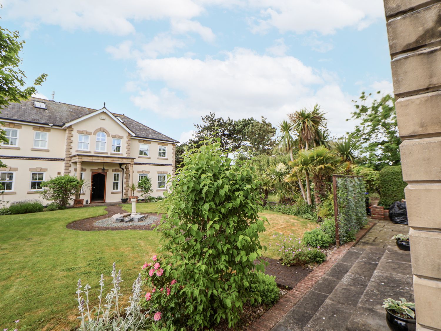 A garden with a house and pathway at Mount House Bryniau near Dyserth