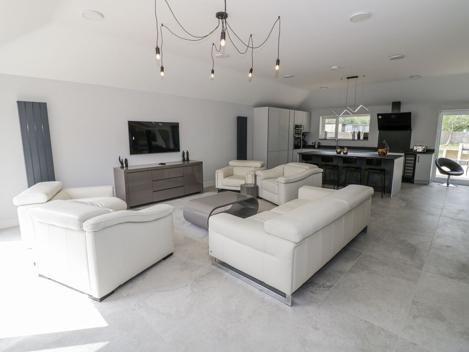 A living room with a television and kitchen island at Chillon South Littleton near Honeybourne