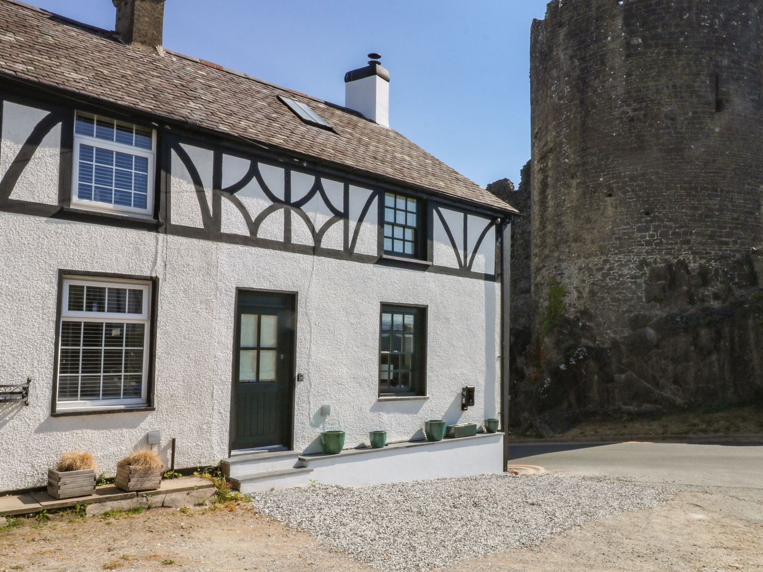 An exterior view of a house with planters and a castle wall at Hilltop Cottage in Conwy