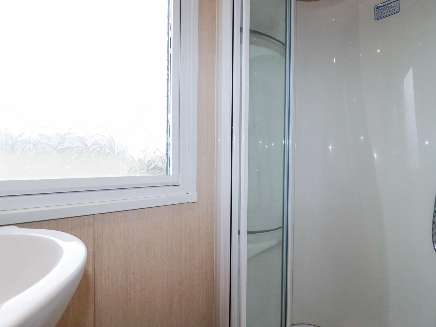 A bathroom with a shower enclosure, a sink, and a frosted window at No 15 Maple Forest White Cross Near Newquay