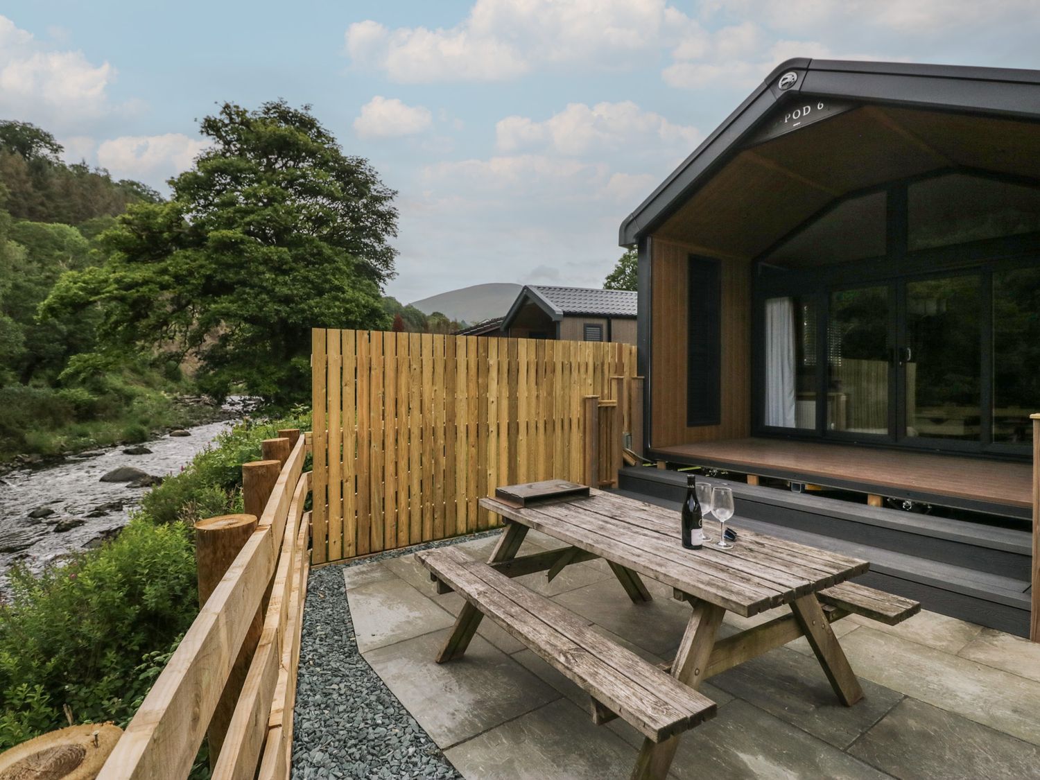 An outdoor area with a picnic table and wine setup at Sail Luxury Family Pod in Keswick