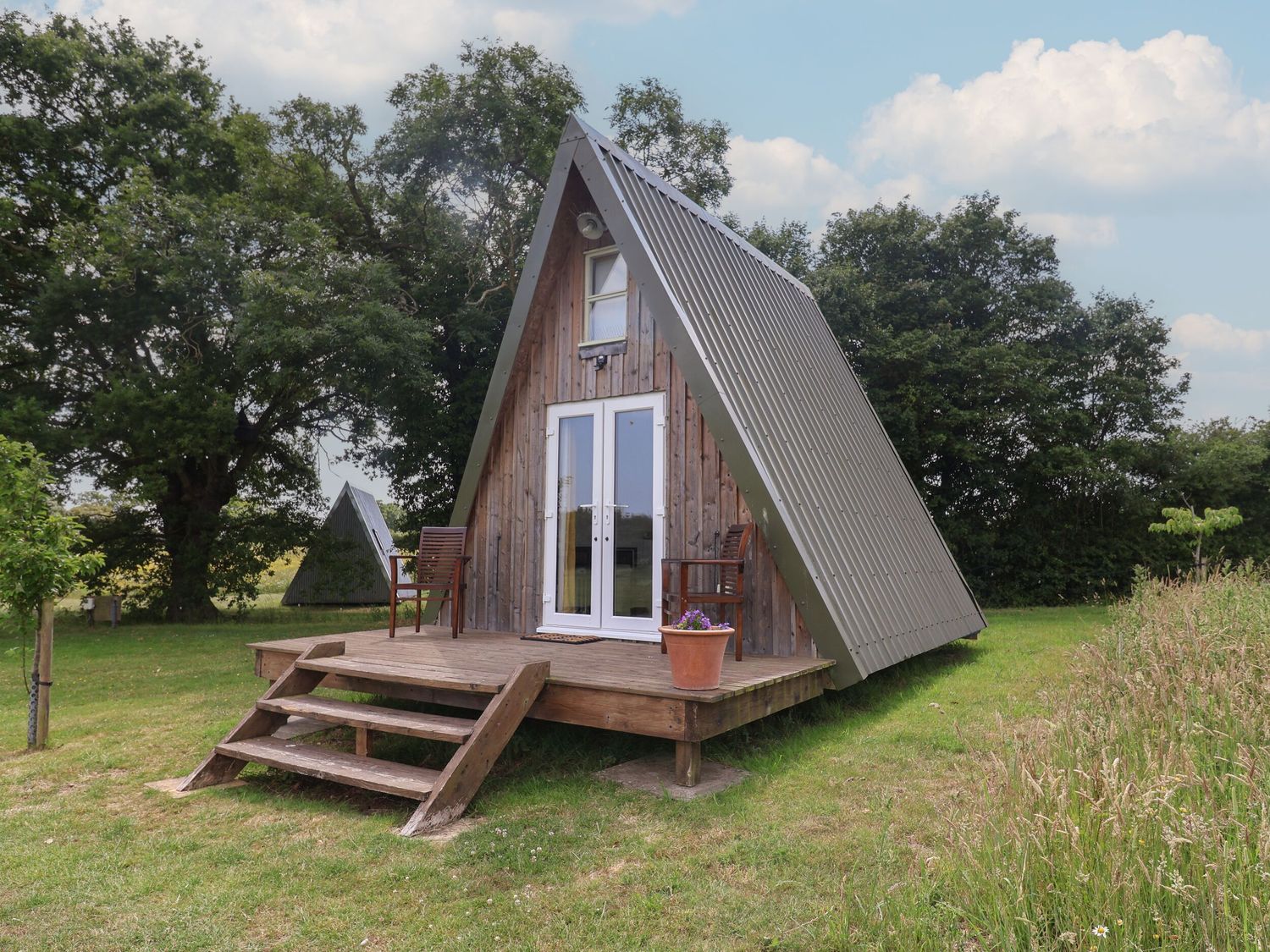 An A-frame house with a wooden deck and chairs at A-frame in Monewden near Otley, Suffolk