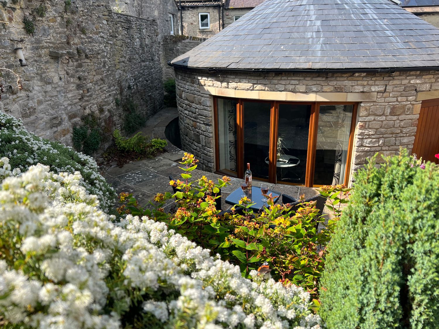 An outdoor area with stone walls and furniture at Poppy's Footprint in Leyburn