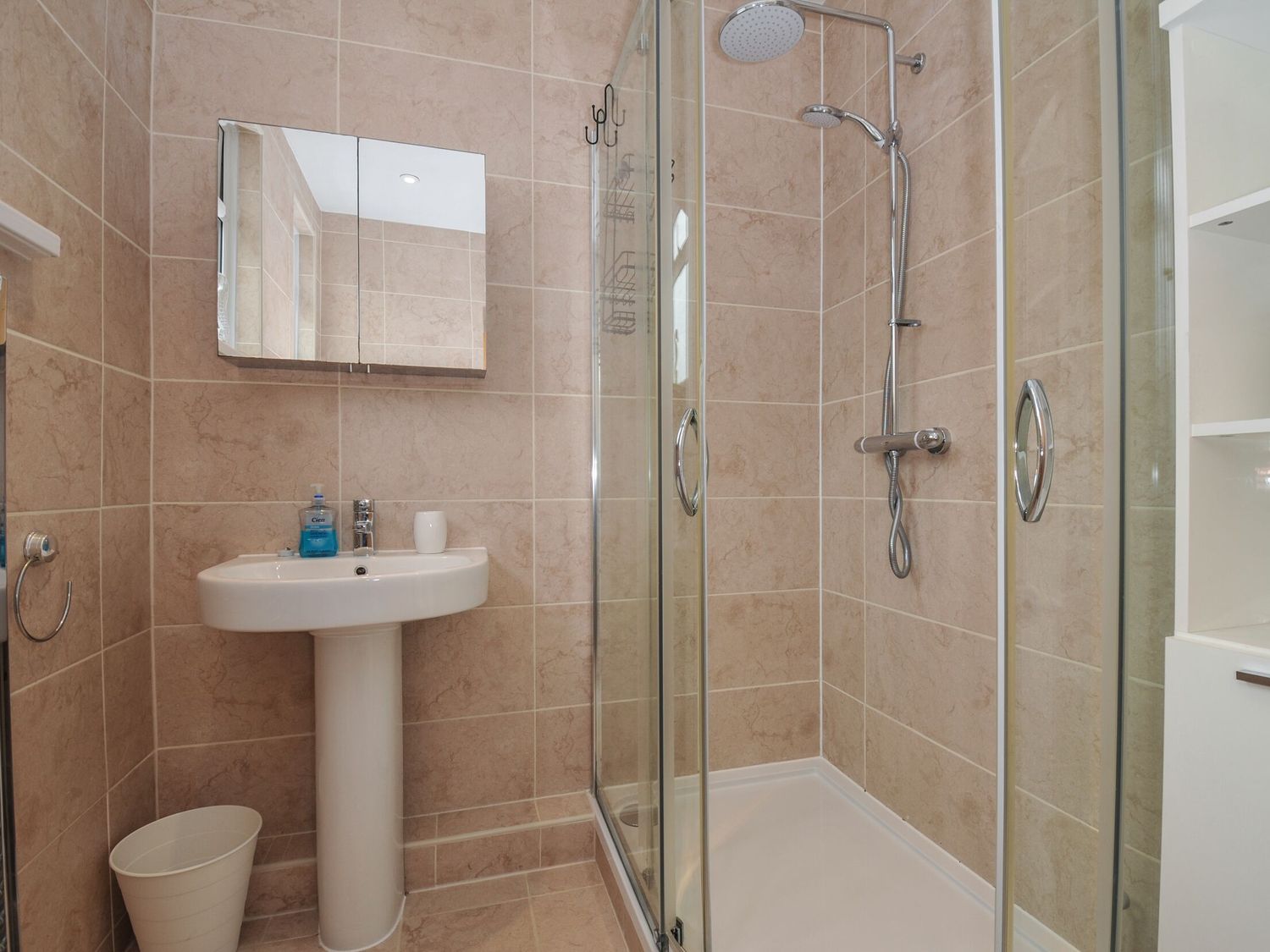 A bathroom with a pedestal sink a wall-mounted mirror cabinet a glass-enclosed shower and tiled walls at Falmouth Bay 2 in Falmouth