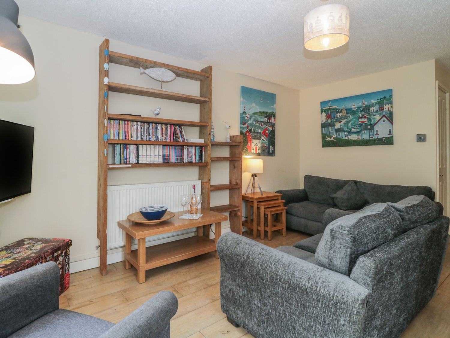 A living room with grey sofas wooden shelves and two paintings on the wall at 26 Manorcombe St Ann's Chapel Cornwall