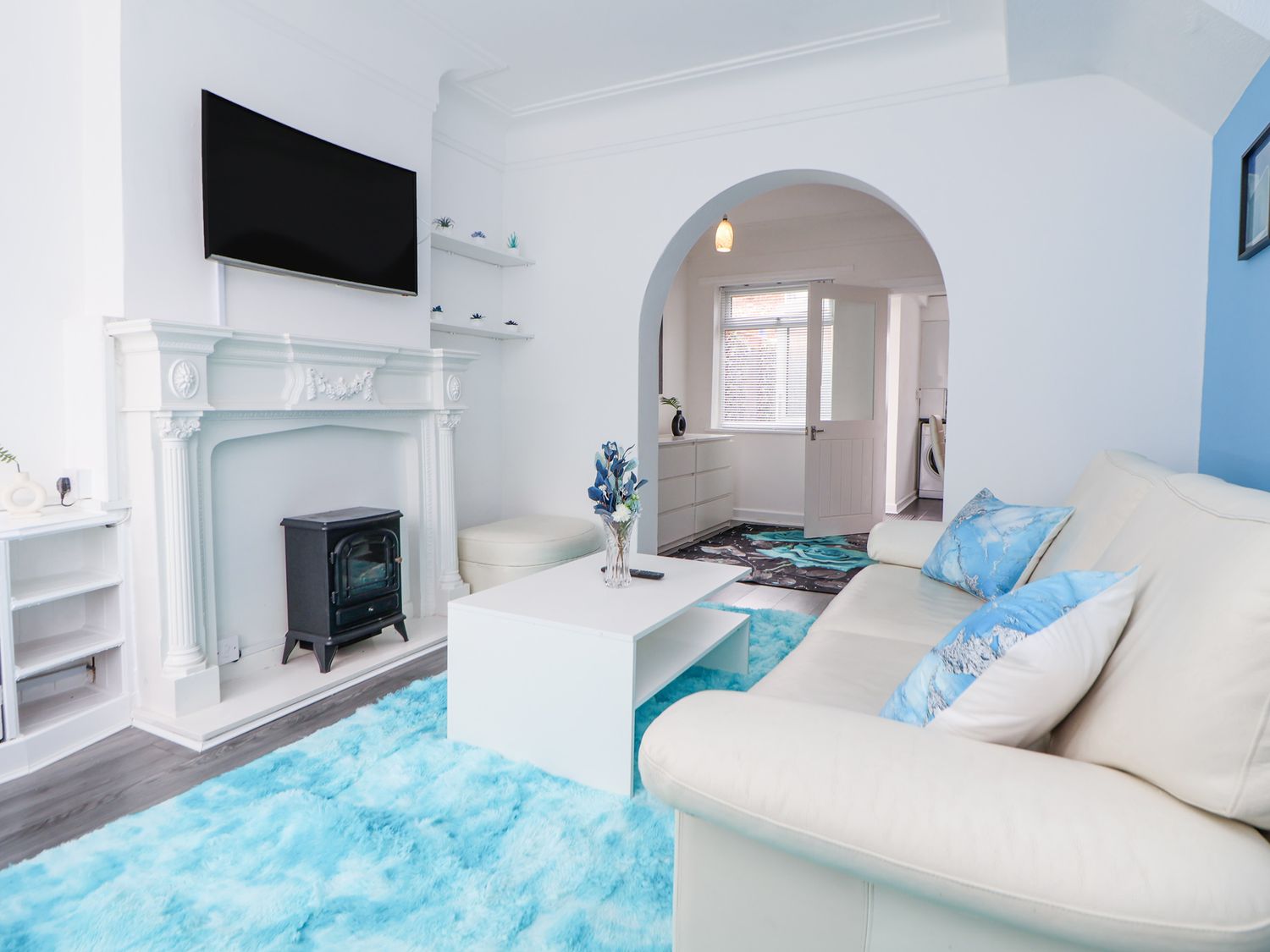 A living room with a white sofa and blue pillows a white coffee table and a blue rug at Anfield Stadium Short Stay and Free Parking in Liverpool