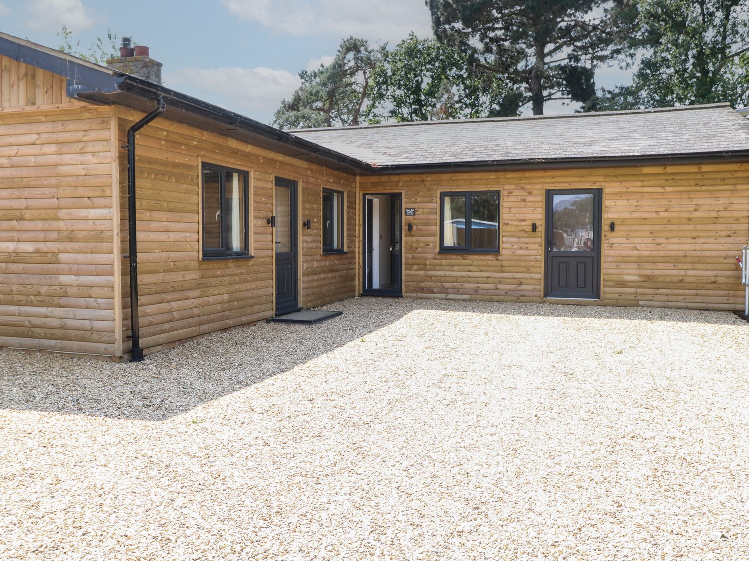An exterior view of a wooden building with gravel at Barn Owl Lodge