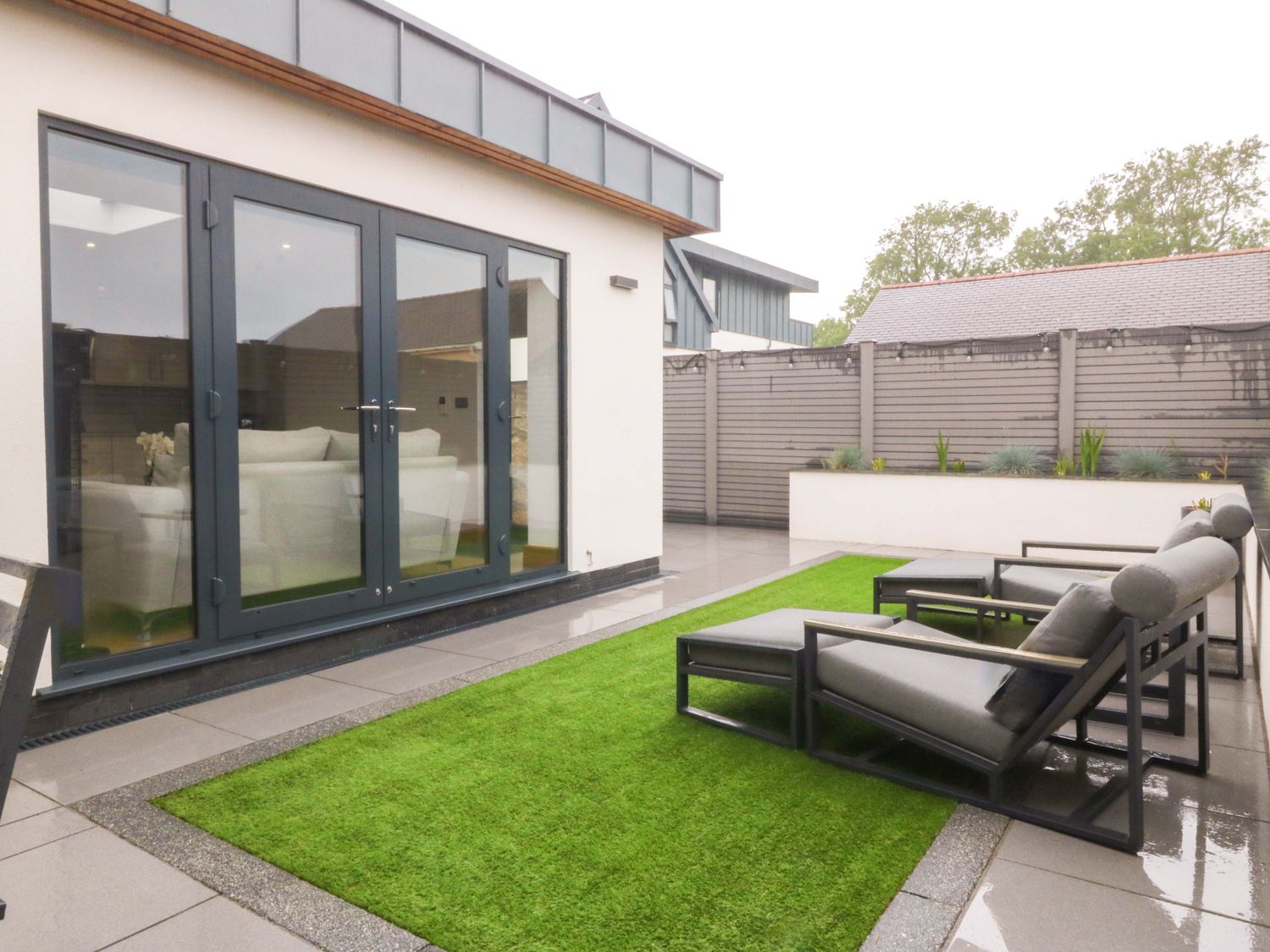 An outdoor space with sliding doors and patio chairs at Lodge in Llangefni