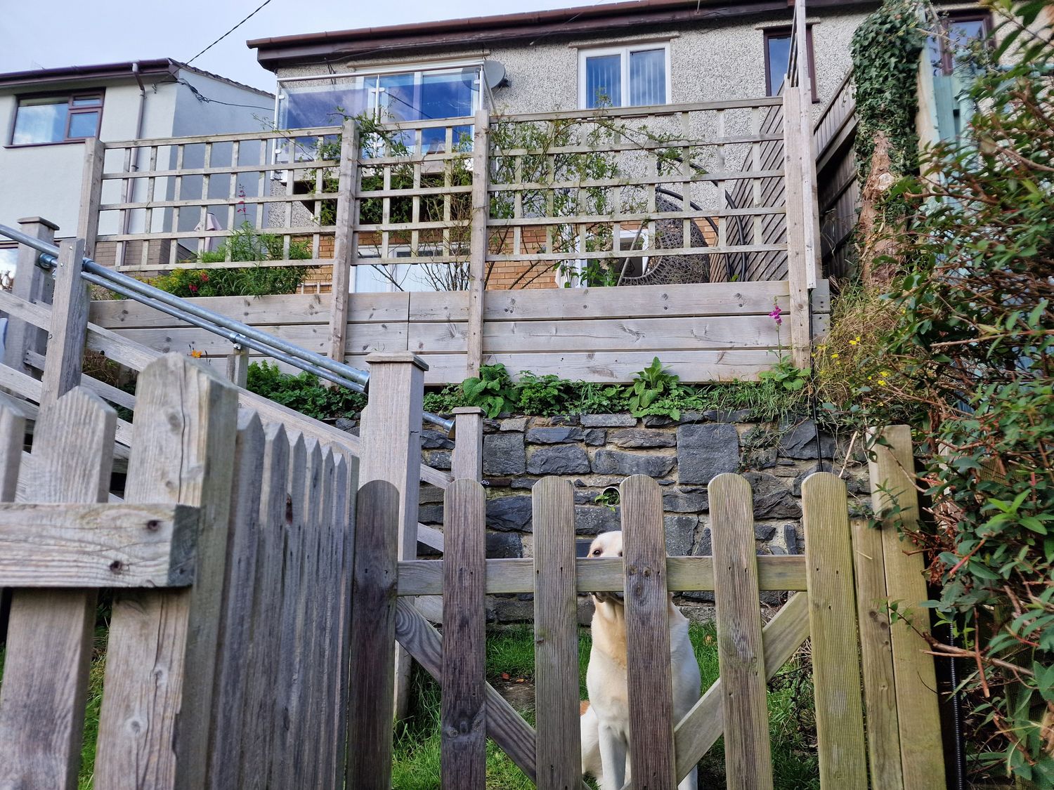 An outdoor area with a wooden fence and steps leading to a house at Golygfa Abergele