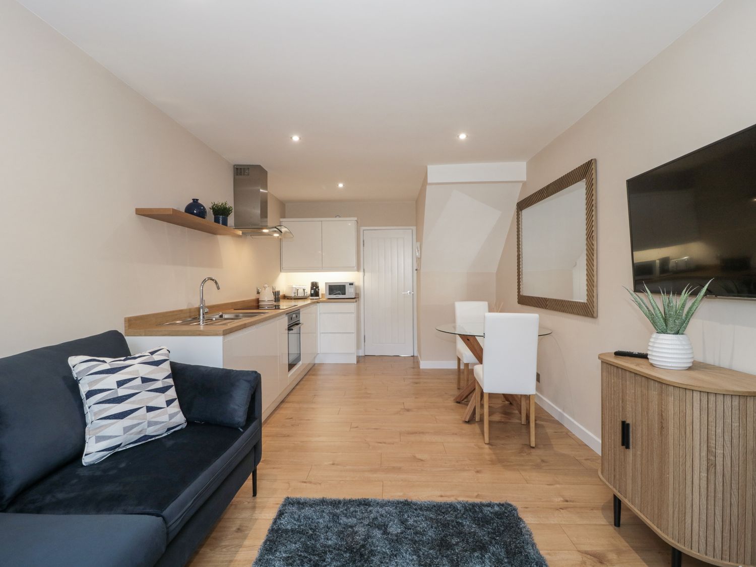 A living room with a sofa, table, and kitchen area at Royal Terrace Sunset in Weymouth