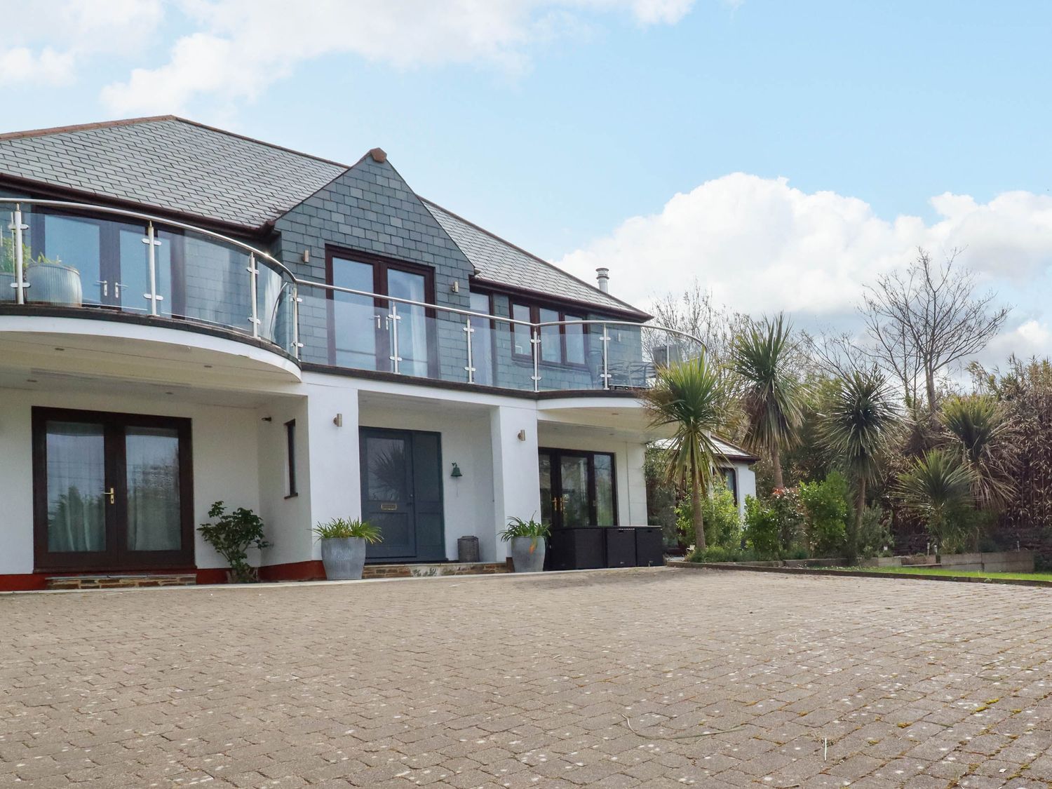 The exterior of a two story house with a paved driveway and glass balcony at Goatsland in Trebetherick