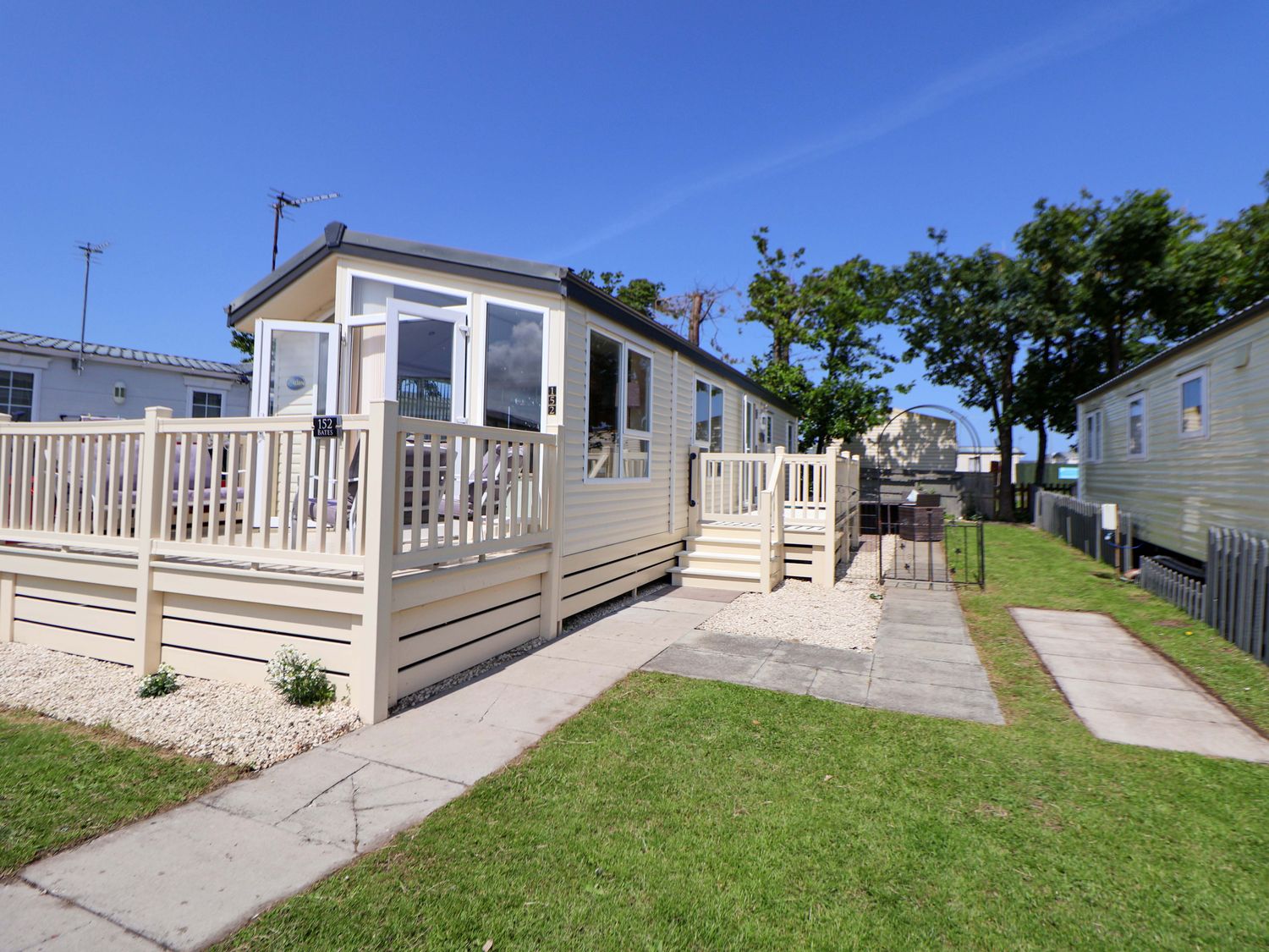 A mobile home with a deck and pathway at 152 Central Park in Prestatyn