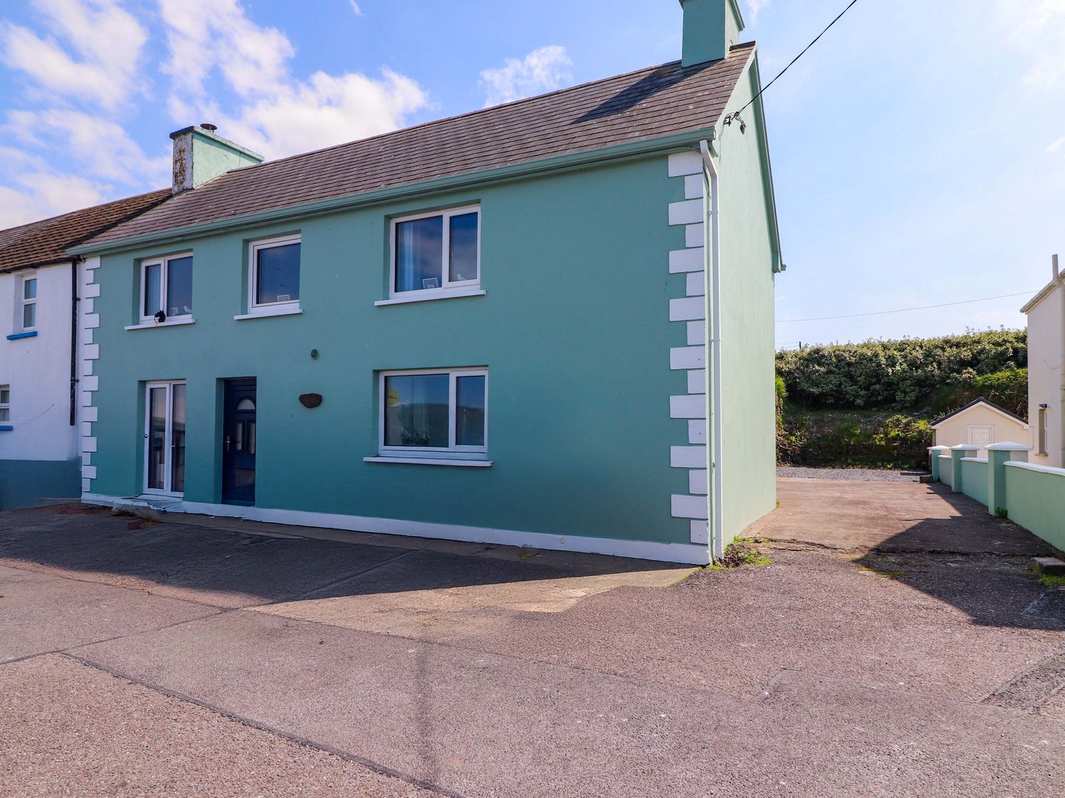 A house with green exterior and driveway at O'Conells in Portmagee