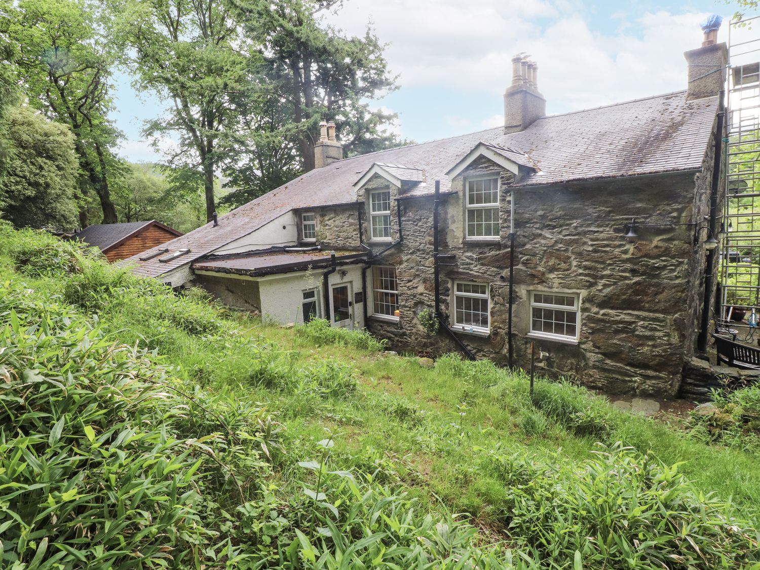 An exterior view of a house with trees and garden at Sygun Cottage Nant Gwynant