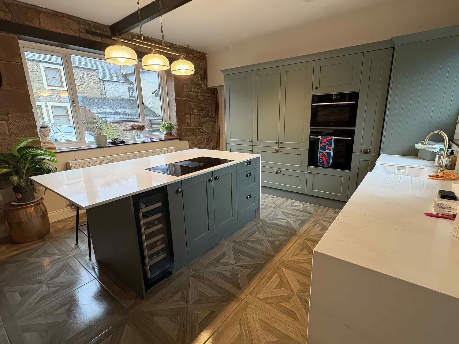 A kitchen with an island, sink, oven and cabinets at Yew Tree Cottage