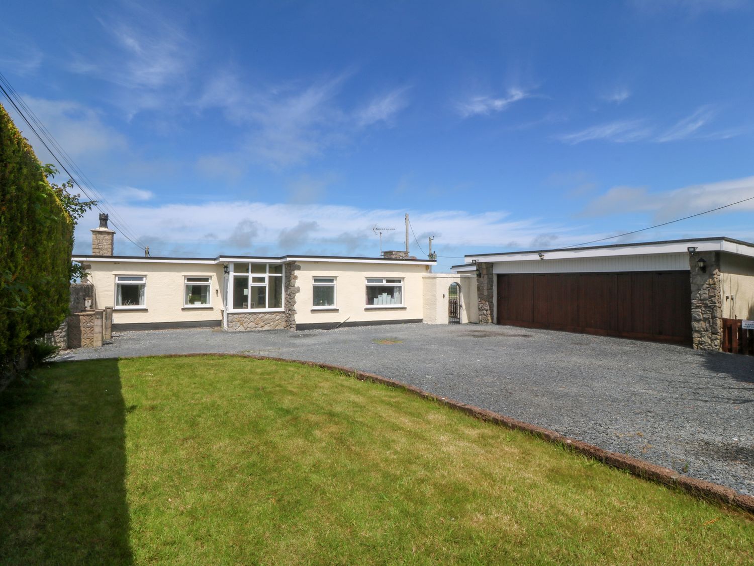 An exterior view of a house with a garage at Llain Delyn Capel Mawr near Malltraeth