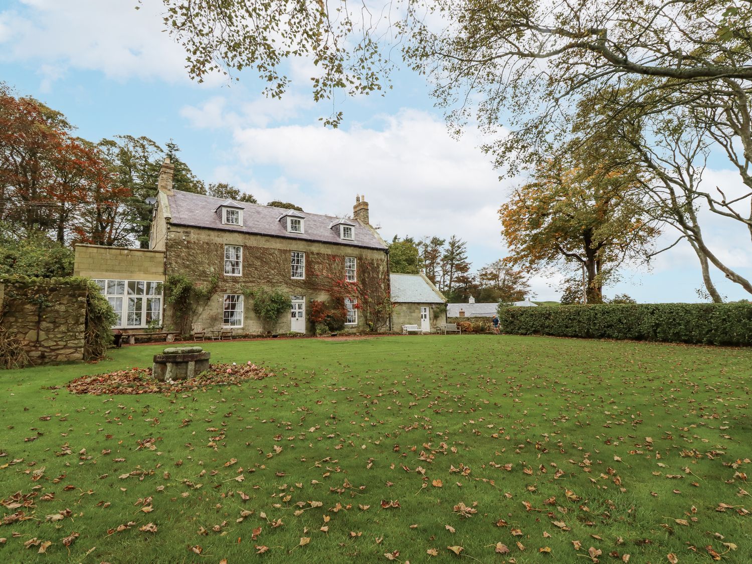 A house with a garden and trees at Elford Farmhouse Seahouses