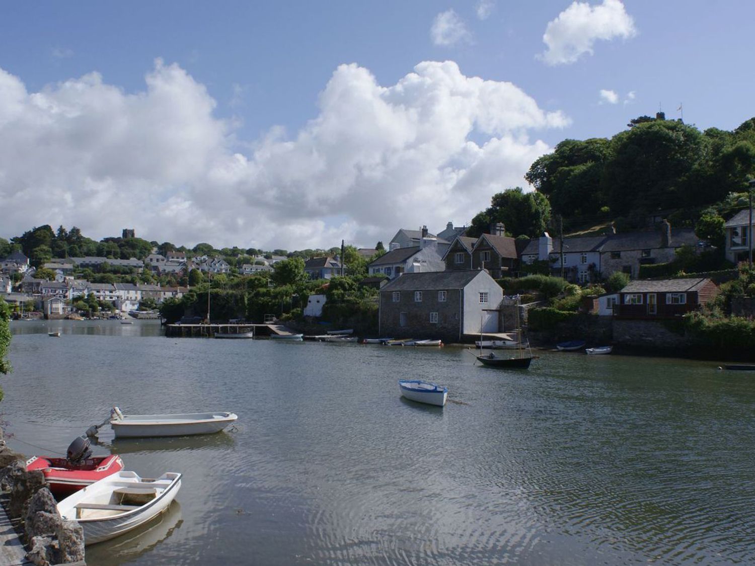 A river with small boats and houses along the shoreline at Tidal Waters in Noss Mayo
