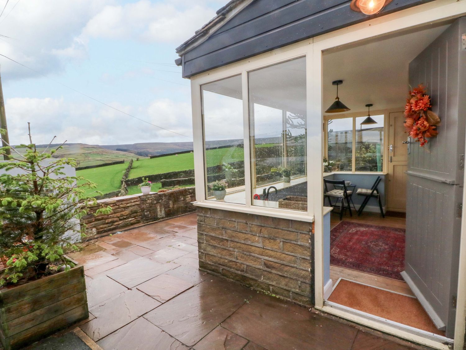 A sunroom with a table and chairs at Stone & Fleece Cottage in Holmbridge
